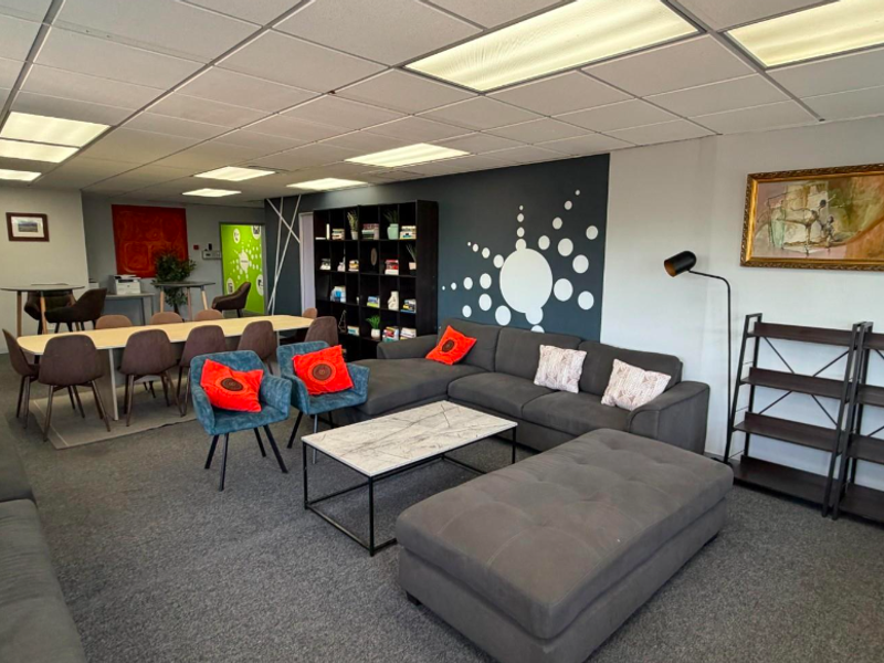 Spacious open-plan office area featuring a suspended ceiling with recessed lighting and carpeted flooring, suitable for collaborative work or lounge settings.
