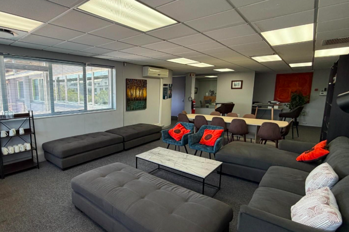 A spacious, well-lit office area featuring a suspended ceiling, recessed lighting, air conditioning, and large windows with venetian blinds.