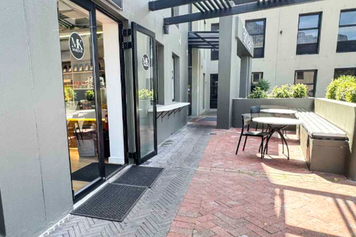 A well-maintained outdoor patio area featuring brick paving, a pergola structure, and a built-in bench, providing an inviting entrance to the office space.