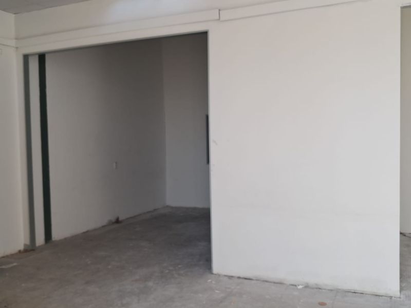 An empty, unfinished industrial utility space featuring concrete flooring and partition walls, suitable for storage or workshop conversion.
