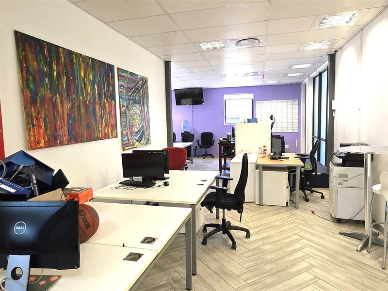 A functional office space featuring a suspended ceiling, recessed lighting, and modern herringbone flooring, providing a bright and professional work environment.