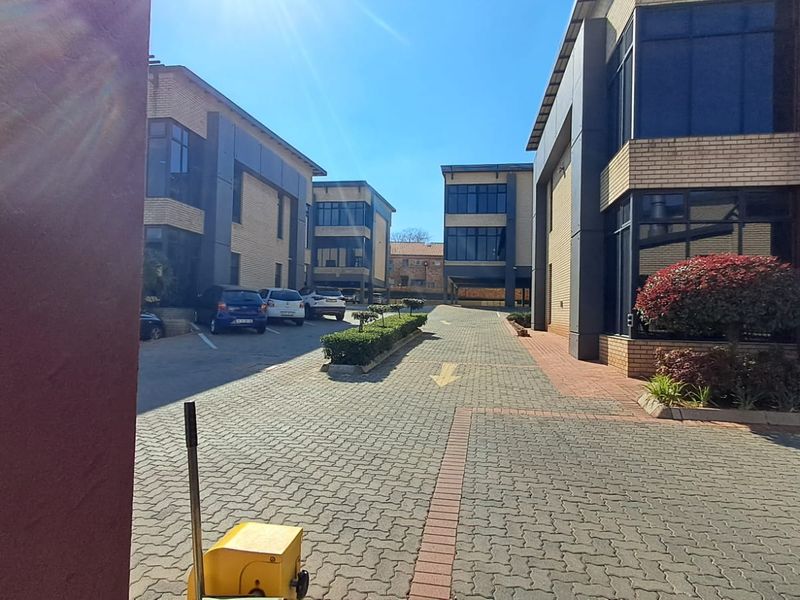 Exterior view of a modern multi-story office complex featuring paved driveways, brick facades, and large glass windows.