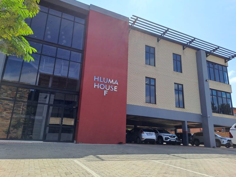 Modern office building exterior featuring a prominent glass facade, brick detailing, and a convenient covered parking area at the entrance.
