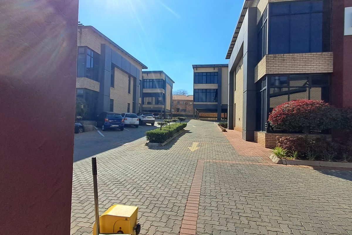 Exterior view of a modern multi-story office complex featuring paved driveways, brick facades, and large glass windows.