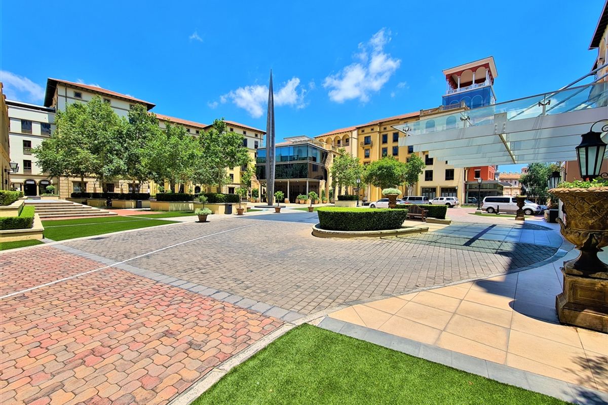 A well-maintained outdoor courtyard area featuring paved walkways, landscaped garden beds, and modern architectural elements within a professional office complex.