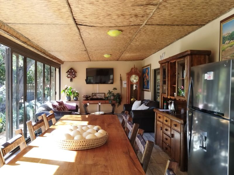 Spacious open-plan living and dining area featuring a unique thatched ceiling, tiled flooring, and large sliding glass doors providing ample natural light.