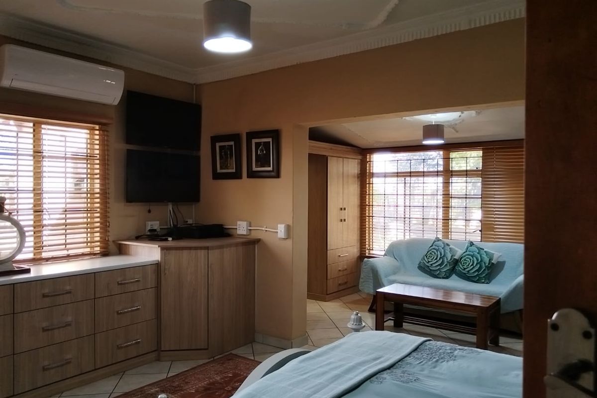 Spacious bedroom featuring tiled flooring, decorative ceiling details, built-in cabinetry, and a wall-mounted air conditioning unit.
