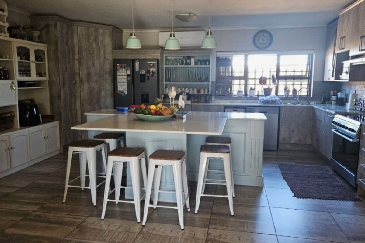 Spacious farmhouse-style kitchen featuring a large central island with quartz countertops, ample built-in cabinetry, modern appliances, and tiled flooring throughout.