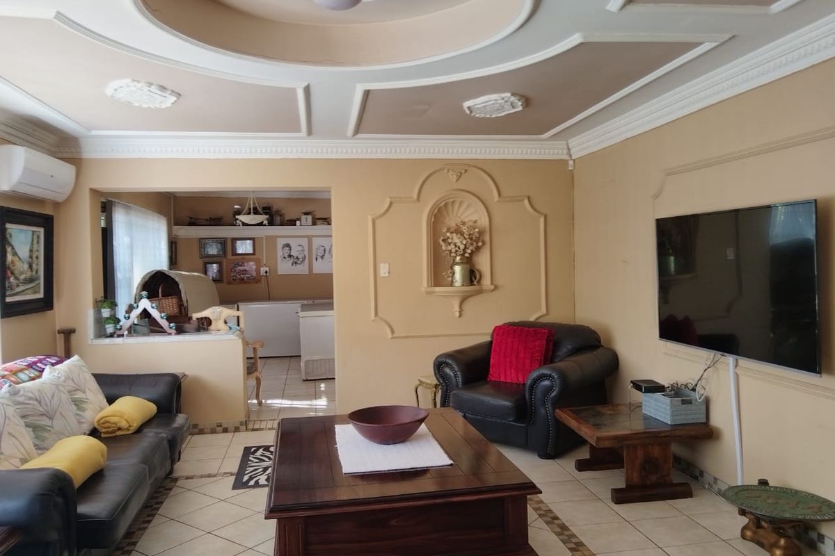 Spacious living room featuring decorative ceiling molding, a built-in wall niche, and tiled flooring, with an open-plan flow into the adjacent kitchen area.