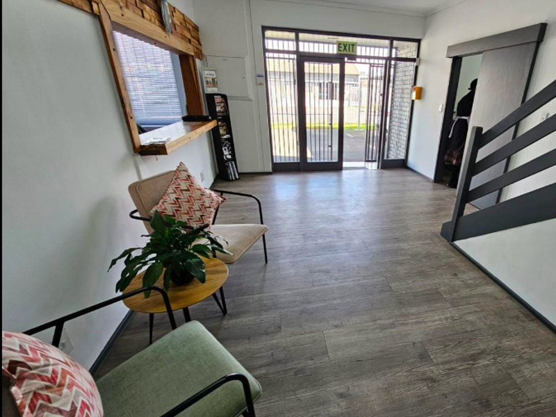 A bright industrial-style entry area featuring timber-look flooring, a decorative timber wall accent, and a secure metal entrance gate.