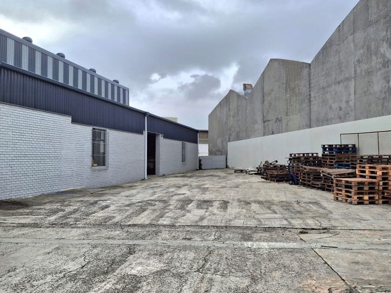 Spacious industrial concrete yard area situated between two warehouse buildings, featuring metal and brick exterior finishes.