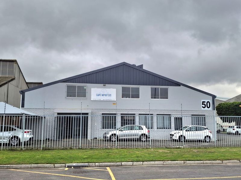 Front elevation of an industrial warehouse property featuring a metal roof, painted brick facade, and secure perimeter fencing.