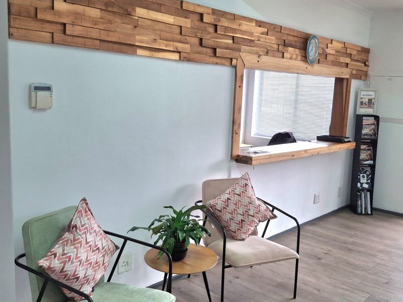 A professional office reception area featuring a decorative wooden wall accent, service window, and durable laminate flooring.