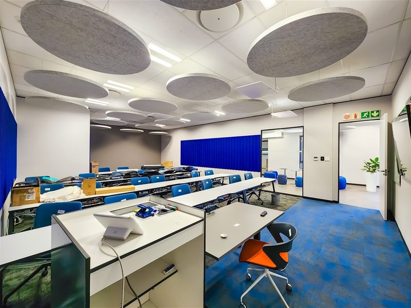 A modern office space featuring suspended acoustic ceiling panels, recessed lighting, and durable carpet tiles, designed for collaborative work environments.