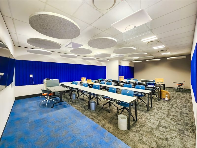 A modern office space featuring suspended acoustic ceiling panels, recessed lighting, and durable carpet tiles, suitable for a collaborative work environment.