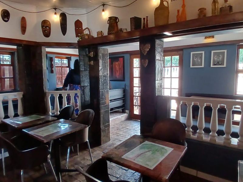 A rustic living area featuring stone-clad pillars, traditional balustrade railings, and brick flooring, creating a warm and characterful atmosphere.