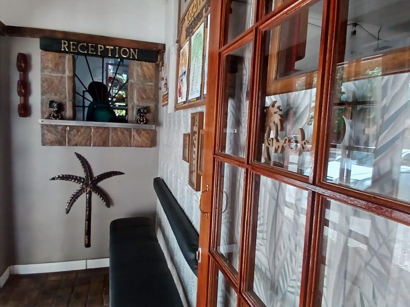 A guest house reception area featuring a stone-clad service window, timber-framed glass doors, and built-in bench seating for visitors.