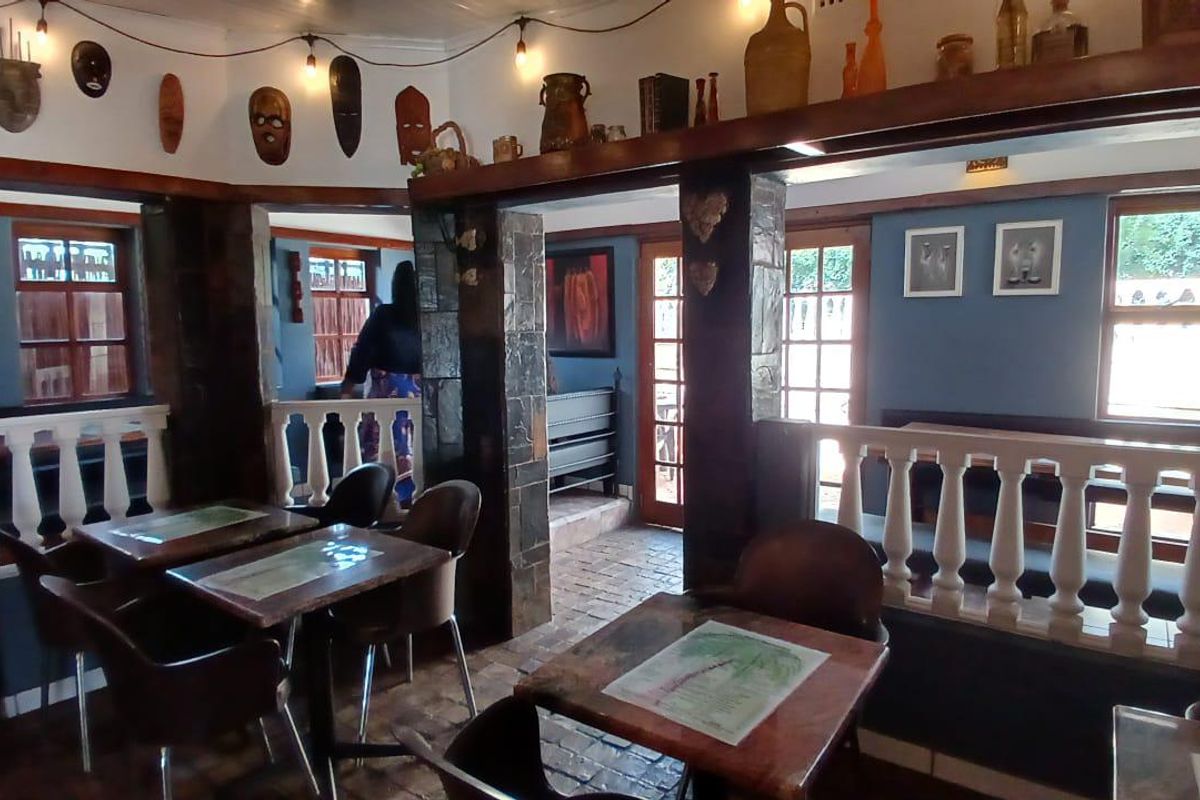 A rustic living area featuring stone-clad pillars, traditional balustrade railings, and brick flooring, creating a warm and characterful atmosphere.
