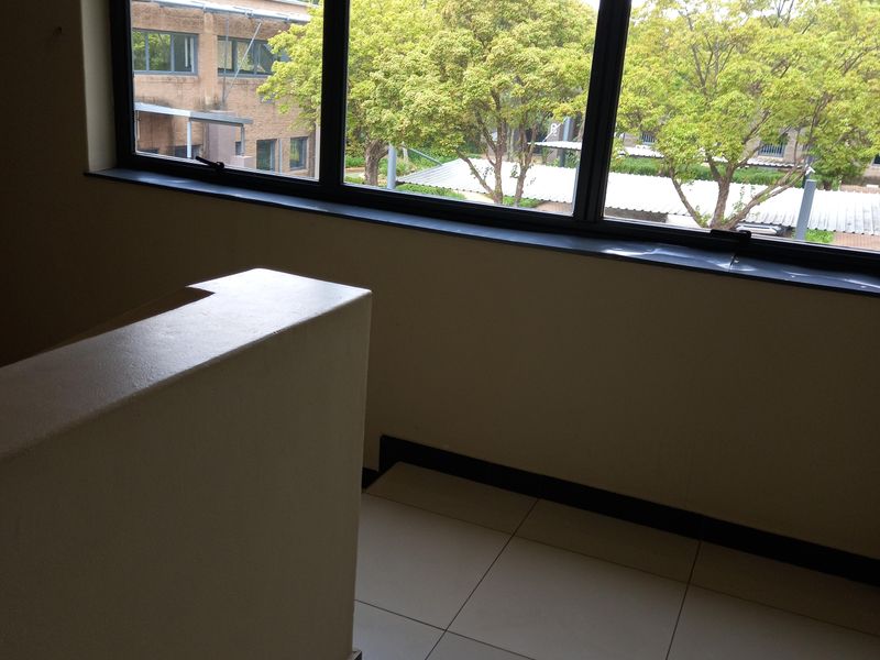 An empty office space featuring large windows with exterior views and clean tiled flooring.