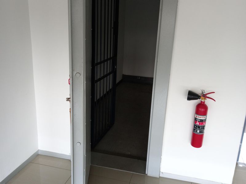 A secure utility or storage room featuring a heavy-duty steel vault door, internal security gate, and wall-mounted fire extinguisher.