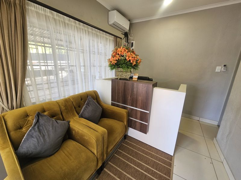 A functional guest house reception area featuring a built-in service desk, tiled flooring, and a wall-mounted air conditioning unit.