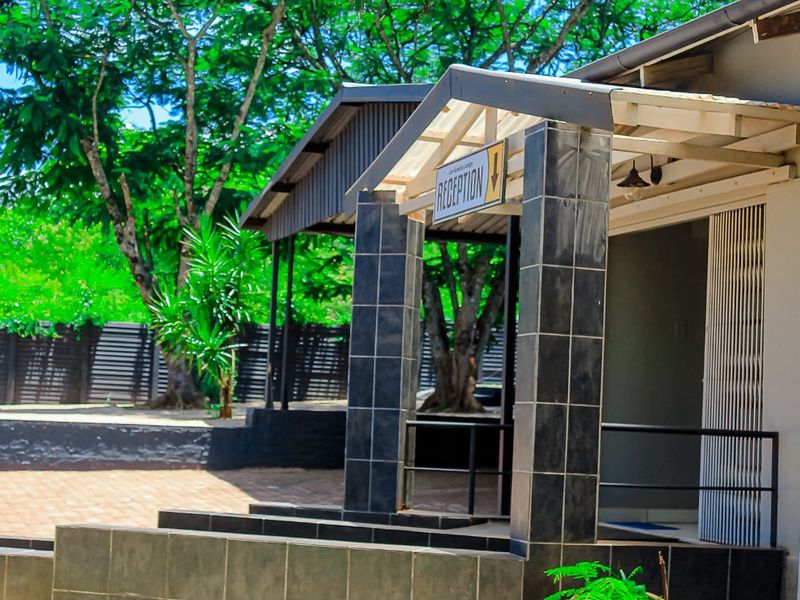 Exterior view of the guest house entrance featuring a covered porch with tiled pillars and paved courtyard area.