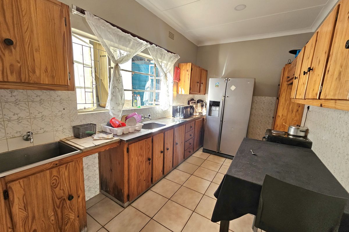 A functional kitchen featuring wooden cabinetry, tiled backsplash, and tiled flooring, offering a traditional layout with ample storage and workspace.