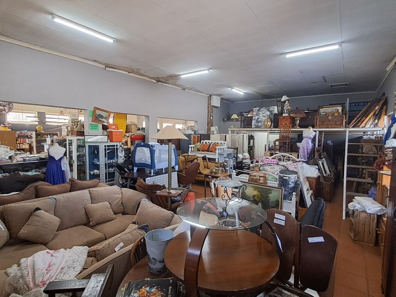 Spacious open-plan retail area featuring a mezzanine level, fluorescent lighting, and tiled flooring, currently utilized for furniture display.