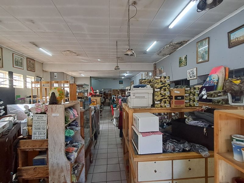Open-plan retail space featuring tiled flooring and fluorescent lighting, currently utilized for merchandise display with visible ceiling maintenance required.