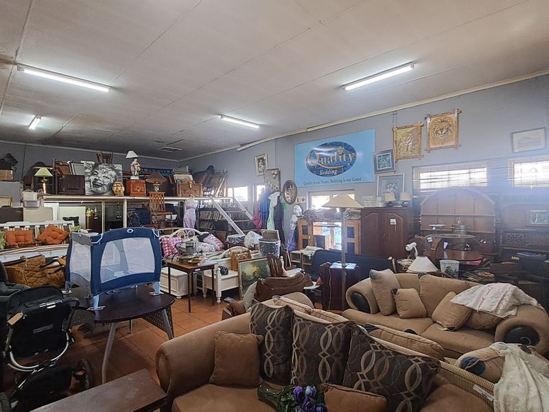 Spacious open-plan retail area featuring tiled flooring, fluorescent lighting, and a mezzanine level, currently utilized for furniture display.