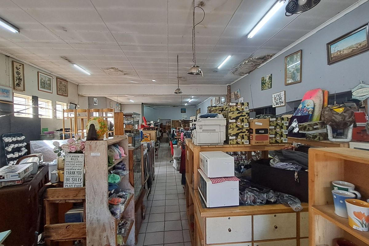Open-plan retail space featuring tiled flooring and fluorescent lighting, currently utilized for merchandise display with visible ceiling maintenance required.
