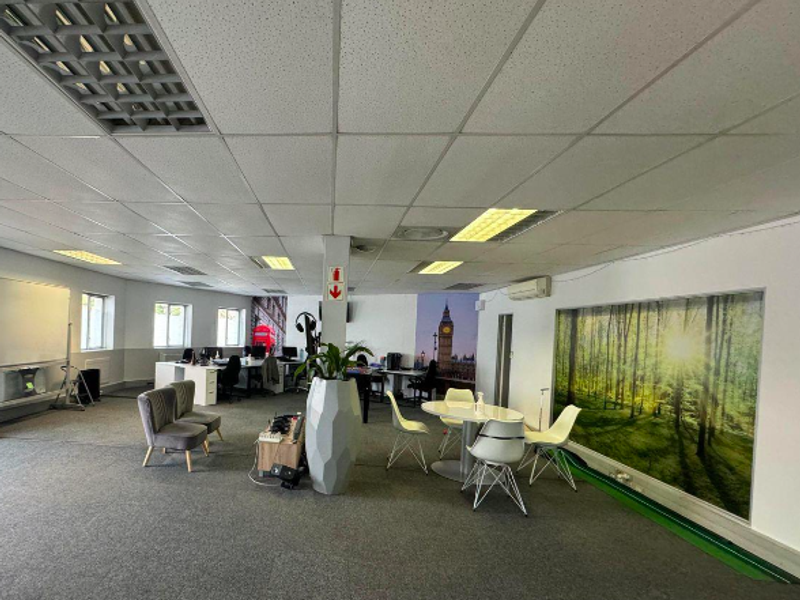 Spacious open-plan office area featuring a suspended ceiling with recessed lighting, air conditioning, and carpeted flooring, suitable for a collaborative workspace.