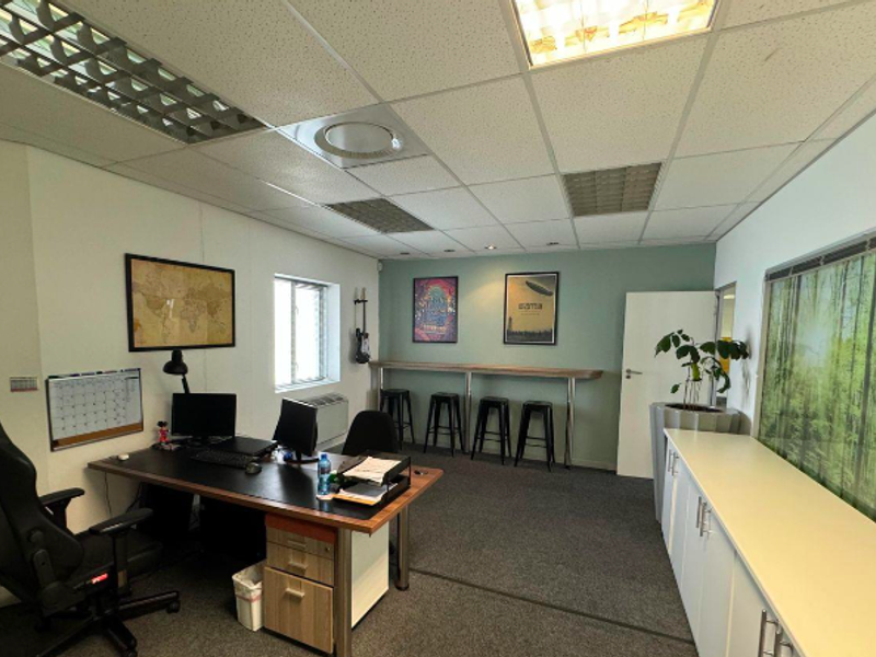 A functional office space featuring a suspended ceiling, recessed lighting, built-in storage cabinetry, and a wall-mounted air conditioning unit.