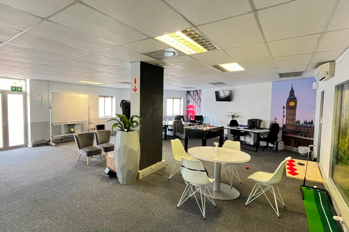 Open-plan office space featuring a suspended ceiling, recessed lighting, carpeted flooring, and a wall-mounted air conditioning unit.