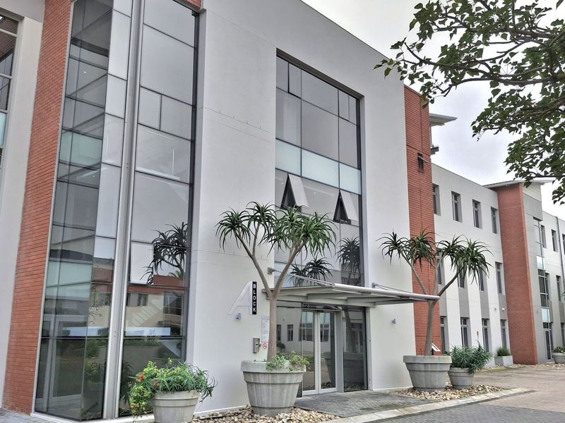Modern office building facade featuring a combination of brick and glass curtain walling with a covered entrance canopy and paved approach.