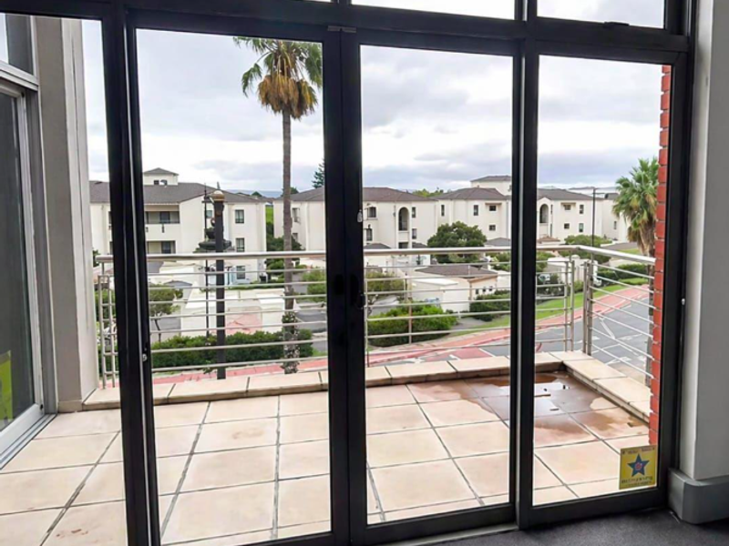 A private balcony featuring tiled flooring and a stainless steel balustrade, offering views of the surrounding residential complex.