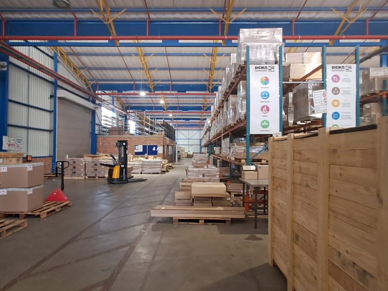 Spacious industrial warehouse facility featuring high-bay ceilings, exposed steel trusses, concrete flooring, and extensive integrated steel racking systems for storage.