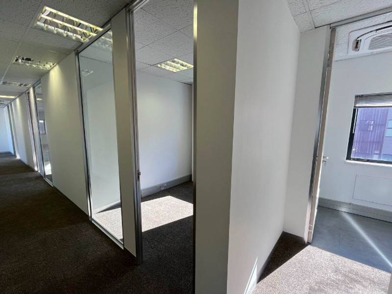 A series of vacant office suites featuring glass partitions, suspended ceilings with recessed lighting, and carpeted flooring in a professional commercial environment.