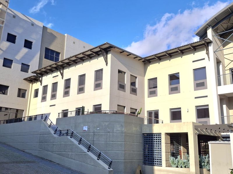 Exterior view of the office building complex featuring a paved driveway, concrete retaining walls, and multi-level architectural design.