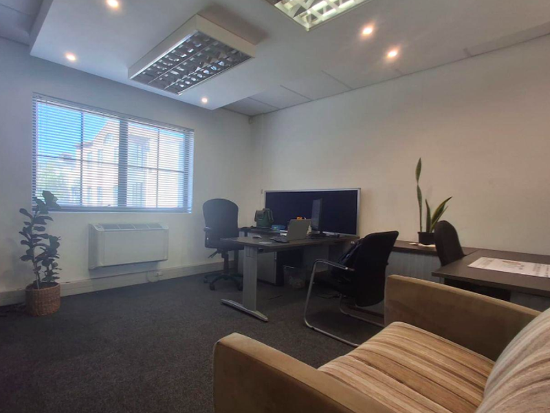 A functional office space featuring recessed lighting, wall-mounted HVAC unit, and carpeted flooring, providing a professional environment for work.
