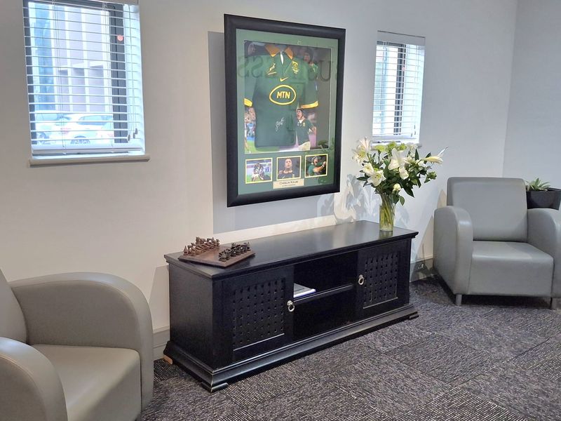 A professional office space featuring neutral walls, carpeted flooring, and dual windows with venetian blinds.