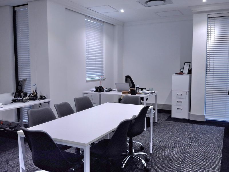 A professional office space featuring recessed downlighting, venetian blinds, and modern carpet flooring, providing a clean and functional work environment.