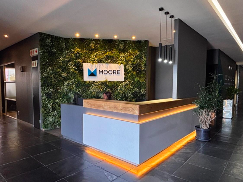 Modern office reception area featuring a custom reception desk, integrated LED lighting, and a decorative green feature wall.