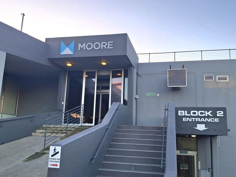 Exterior view of the Block 2 office entrance featuring concrete stairs, an access ramp, glass doors, and clear building signage.