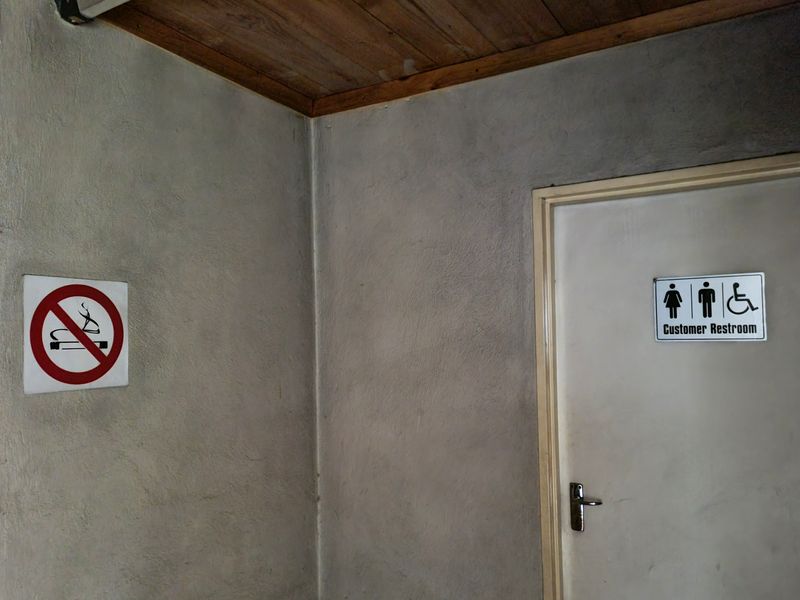A commercial hallway featuring a timber ceiling and a designated accessible customer restroom door.