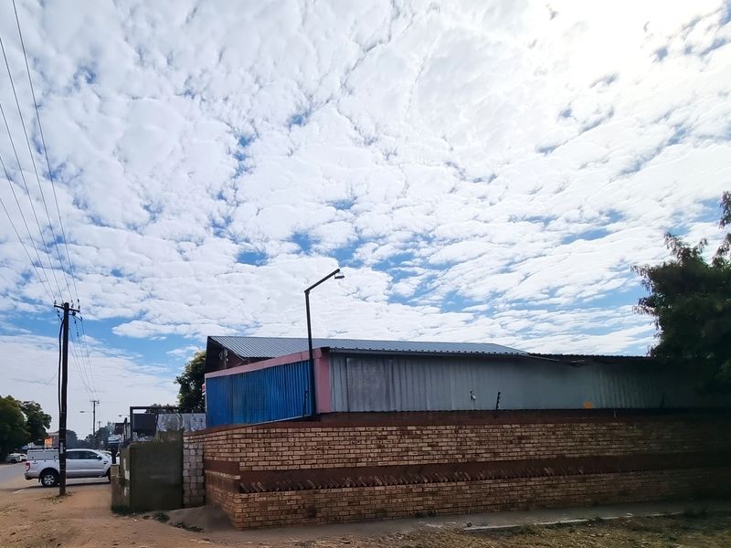 Exterior view of a commercial property featuring a corrugated metal roof, brick boundary wall with security spikes, and metal cladding.