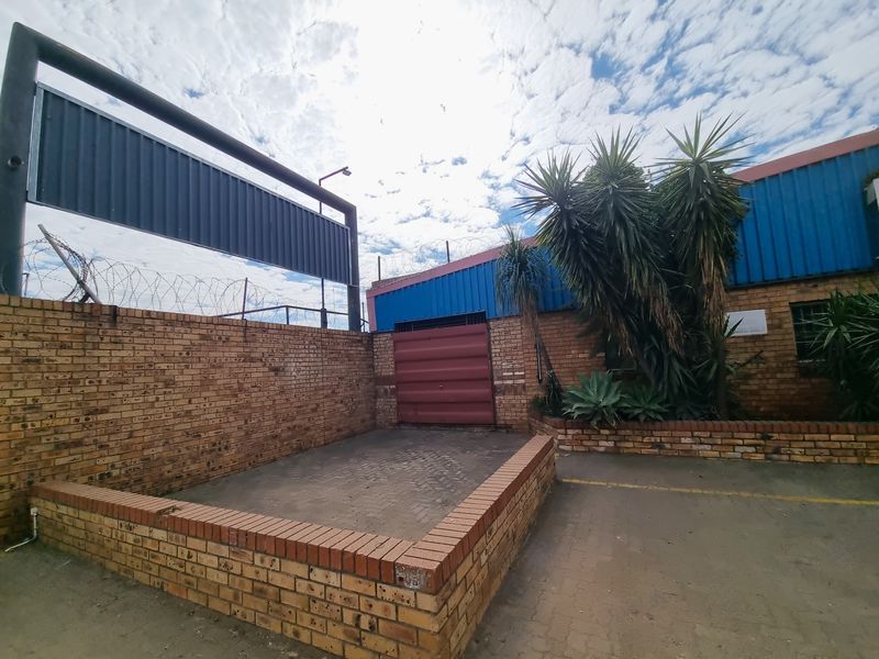 Rear exterior courtyard area featuring face brick walls, a metal roller shutter door, and secure perimeter fencing with razor wire.