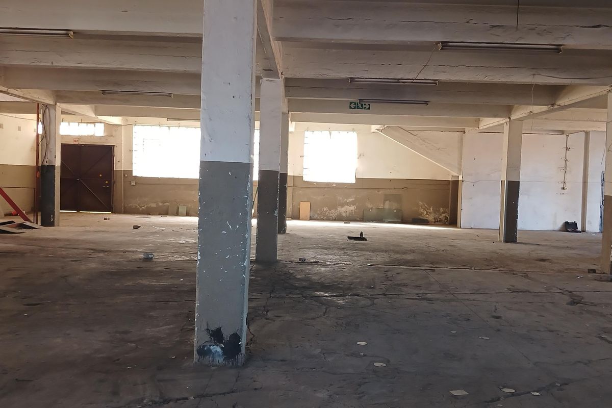 Expansive industrial warehouse space featuring high ceilings, concrete flooring, and structural support columns, suitable for storage or manufacturing operations.