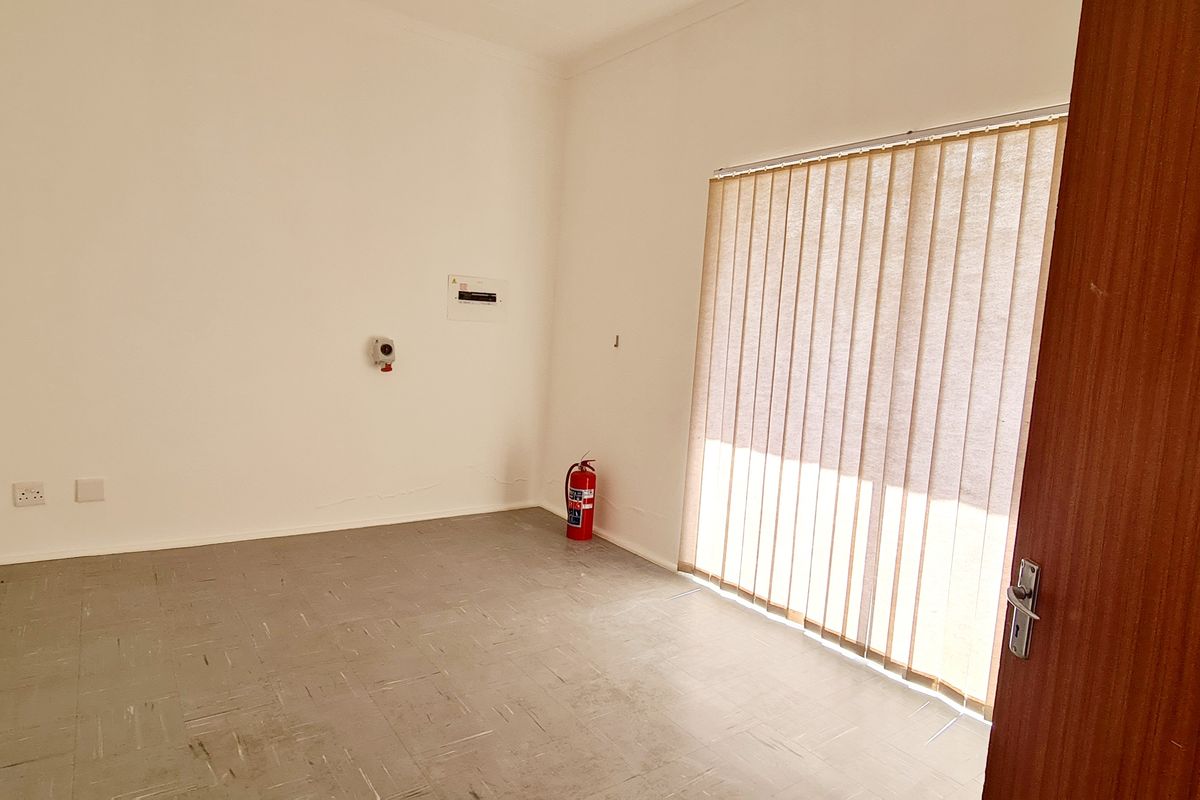 A vacant office or utility space featuring tiled flooring, vertical blinds, and built-in electrical distribution board.
