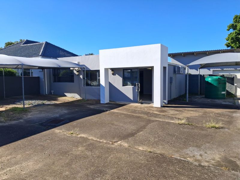 Front exterior view of the office property featuring a paved driveway, shade ports, and a water storage tank.